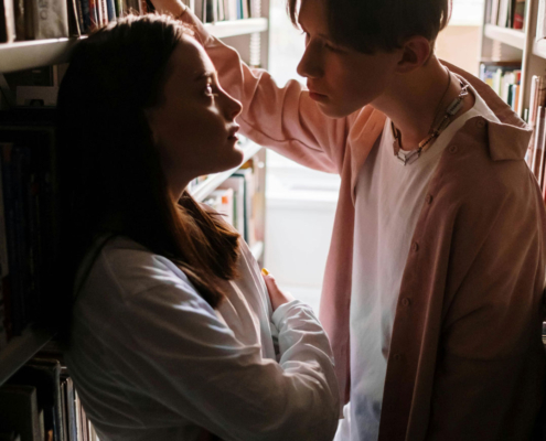 teen boy and girl in library looking at each other