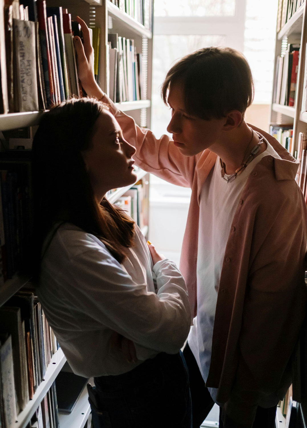 teen boy and girl in library looking at each other