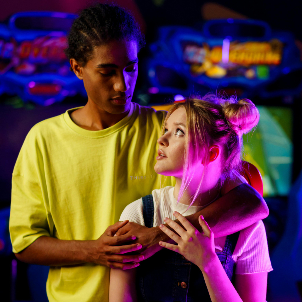 A Man's Arm on a Woman's Shoulder while Looking at Each Other