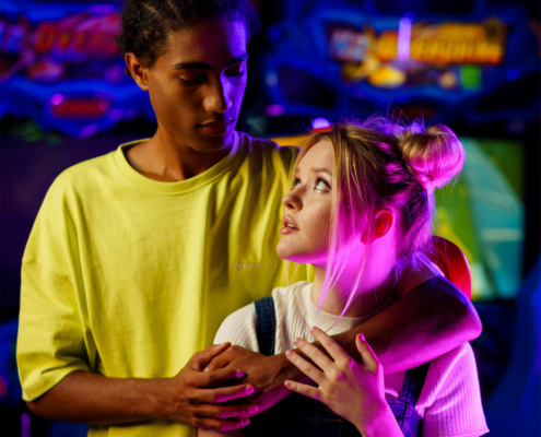 A Man's Arm on a Woman's Shoulder while Looking at Each Other