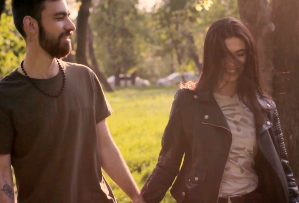 young man and women walking outside in a park holding hands