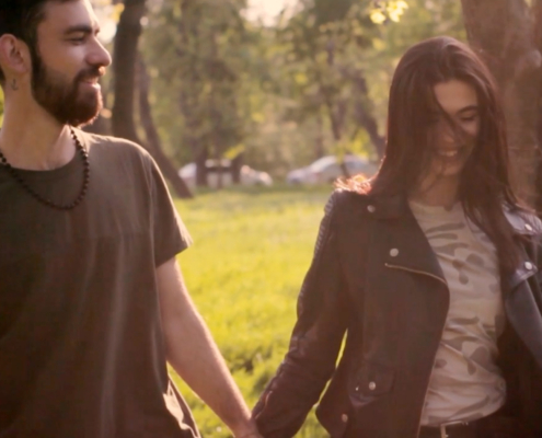 young man and women walking outside in a park holding hands