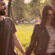 young man and women walking outside in a park holding hands