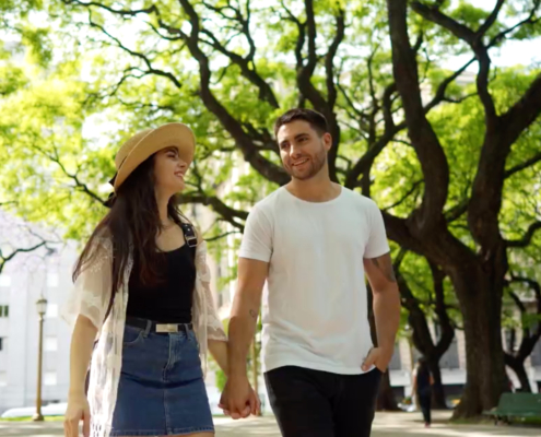 young man and women walking in park holding hands